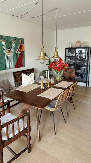 A dining area with a wooden table, chairs, and a painting on the wall. - Apartment with two balconies in Copenhagen (København)