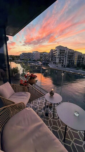 A balcony with outdoor seating, a view of a river, and buildings in the background. - Apartment with two balconies in Copenhagen (København)