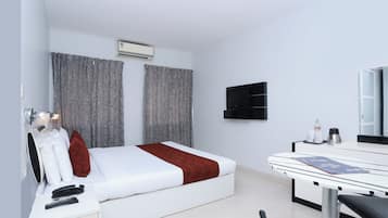 A modern hotel room with a bed, bedside table, and a desk with a chair.