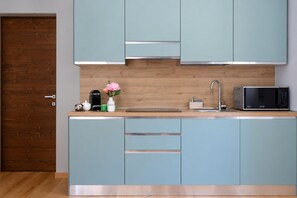 A modern kitchen with light blue cabinets, a wooden countertop, a stainless steel sink, a microwave, and a coffee maker. - Vrbo Property (Cepina)