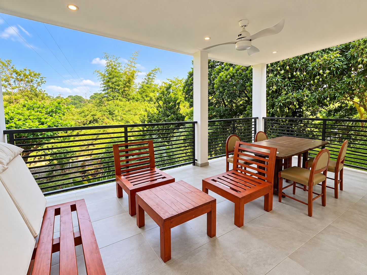 A balcony with a table and chairs, a bench, and a ceiling fan.