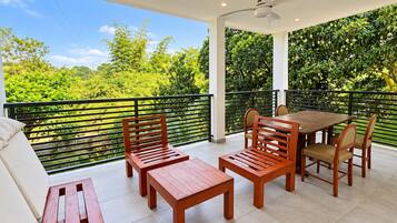 A balcony with a table and chairs, a bench, and a ceiling fan.