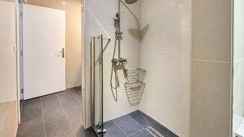 Une salle de bain moderne avec une douche à parois de verre, un porte-serviettes et un drain au sol.