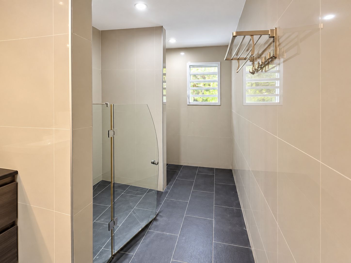 Un baño moderno con cabina de ducha de vidrio, una ventana con vistas y un perchero para toallas.