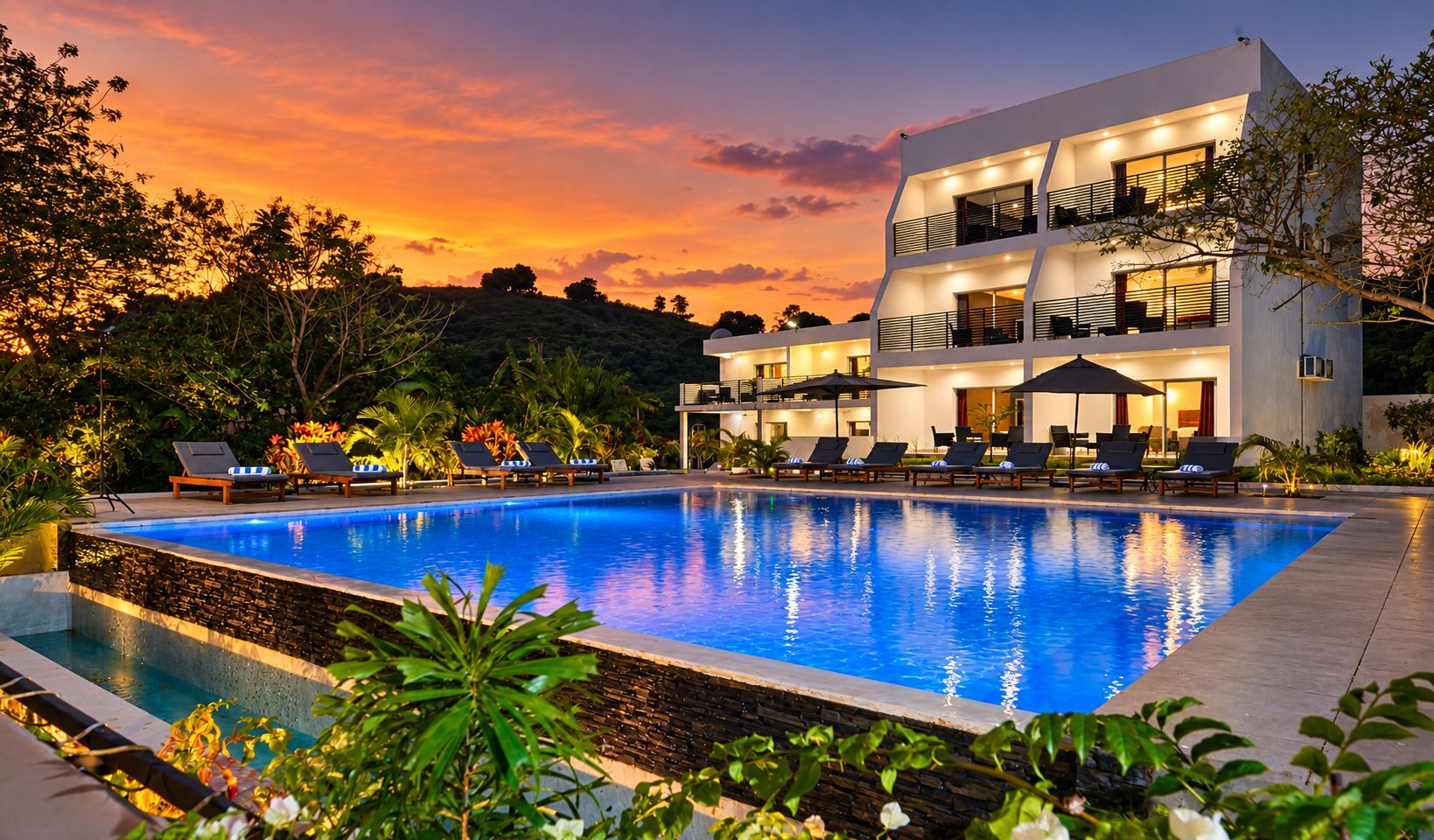 Un hotel moderno con piscina, varios balcones y mobiliario exterior.