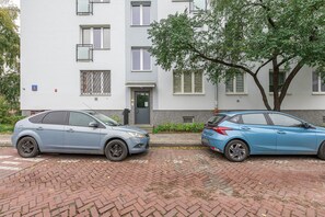 A two-story building with a brick facade, a tree in front, and two parked cars. - Lumina 2room Apart near Old Town Balcony (Warszawa)