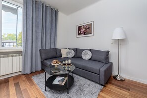 Un salon moderne avec un canapé gris, une table basse en verre et un lampadaire.