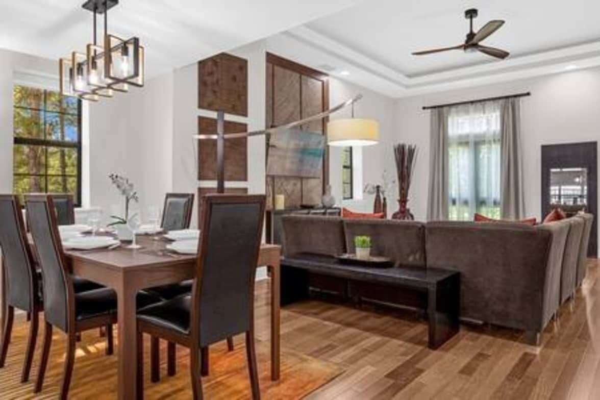 Een moderne eetruimte met een houten tafel en stoelen, een bank en een plafondventilator.