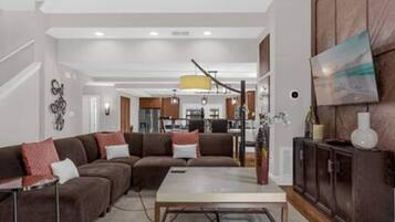 Uma sala de estar moderna com um sofá seccional, uma mesa de centro e um armário.