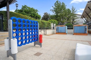 Uma área de estar externa com divisória estampada em azul e branco, um banco branco e uma estrutura listrada em azul e branco.