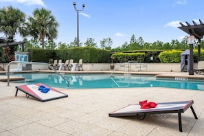 Piscina com espreguiçadeiras e quadra de basquete.