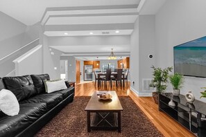 Un salon moderne avec un canapé en cuir noir, une table basse en bois et un grand téléviseur à écran plat.