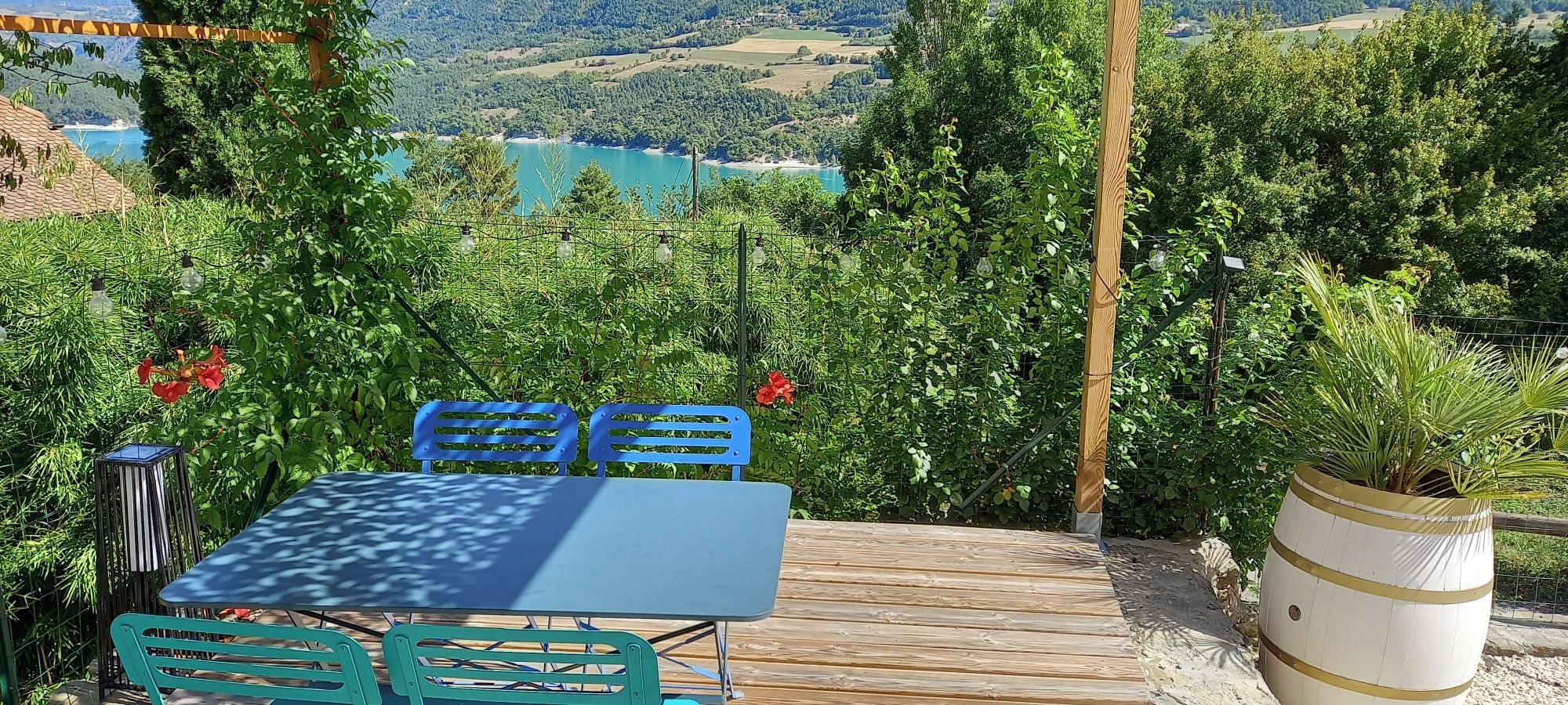 Un espace extérieur aménagé avec une table et des chaises, entouré de verdure et offrant une vue sur un paysage pittoresque.