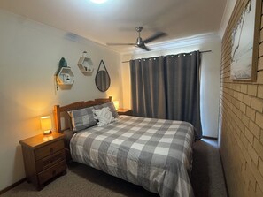 A bedroom with a bed, nightstands, a ceiling fan, and a window with curtains. - 3 bedroom apartment in Evans Head close to shops clubs and beaches. (Evans Head)