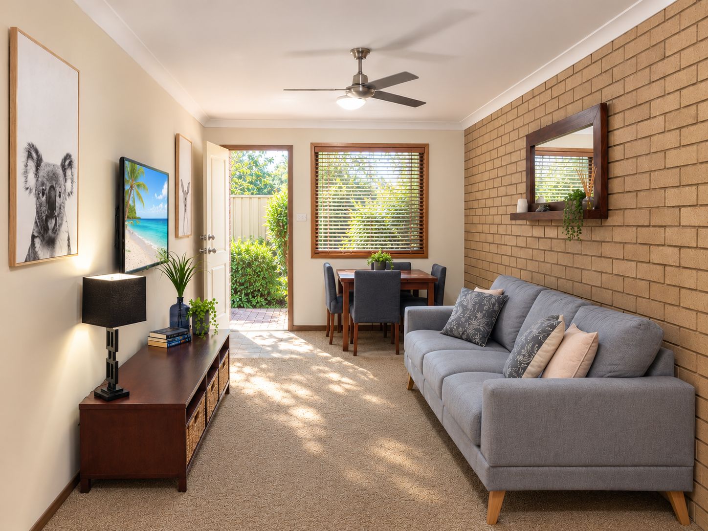 A living room with a sofa, a dining table, and a ceiling fan.
