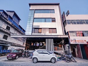 Un edificio moderno con fachada de vidrio, un acceso cubierto y un letrero que indica un restaurante.