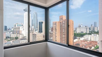 Habitación de esquina con amplias ventanas que dan a una vista urbana con edificios altos.