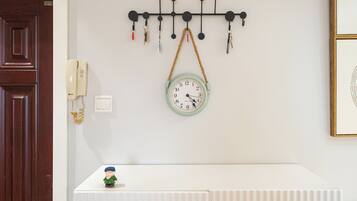A wall-mounted key holder with keys and a clock below it.