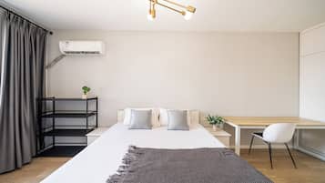 Un dormitorio moderno con cama, mesita de noche, silla y un equipo de aire acondicionado.