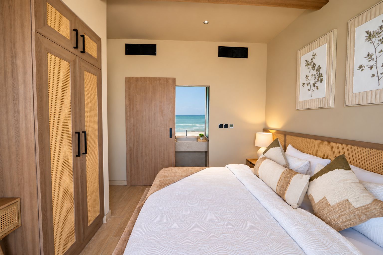 Une chambre d’hôtel avec un grand lit, une vue sur la plage et une armoire en bois.