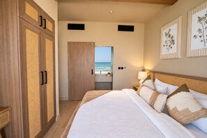 A hotel room with a large bed, a view of the beach, and a wooden wardrobe. - Western Beach Resort (Al Sila)