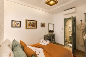 Un dormitorio con una cama, un tocador con espejo y obras de arte en la pared.