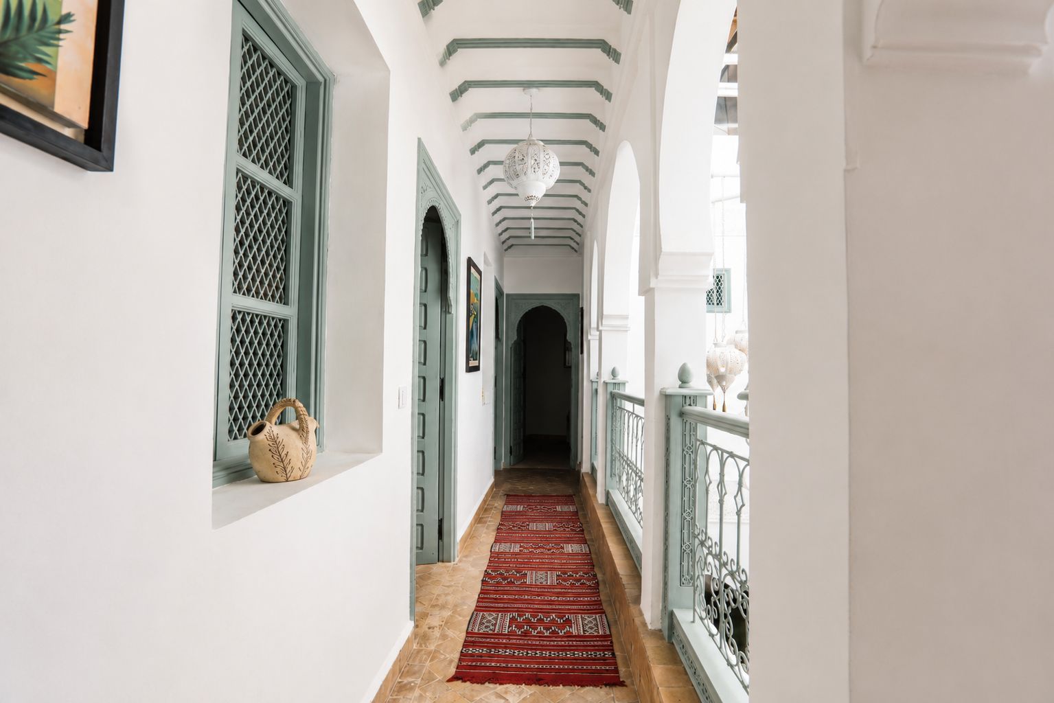 A hallway with a patterned carpet, green door frames, and a white wall.
