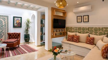 A living room with a sofa, armchair, and a coffee table with a vase of flowers.