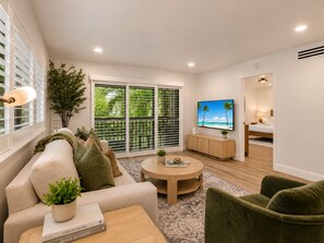 A modern living room with a sofa, coffee table, and a television. - Renovated PGA National Home by Guaranteed Rental (Palm Beach Gardens)