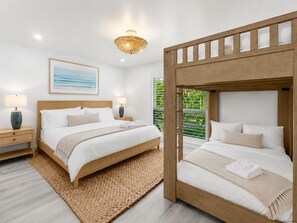Ett hotellrum med en stor säng, en mindre säng, två sängbord, en lampa, en tavla och utsikt över grönområden.
