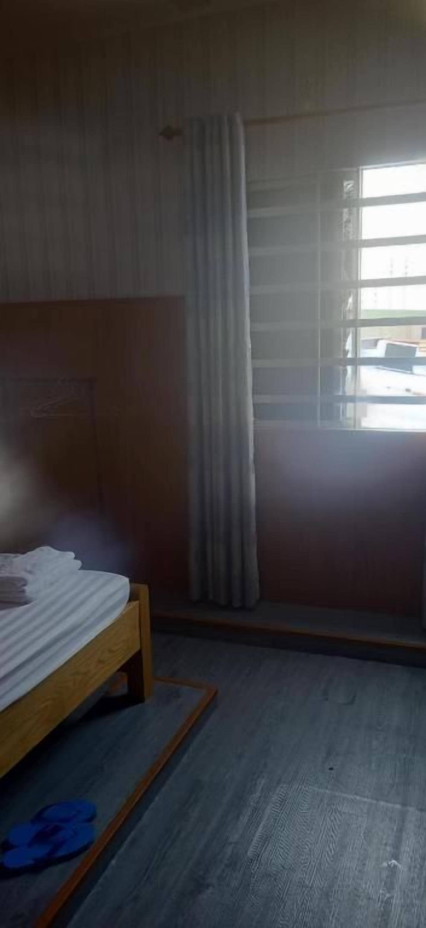A room with a bed, a window with curtains, and a view outside.