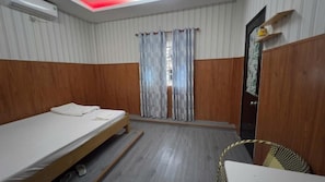 Ein Zimmer mit einem Einzelbett, einem Holzschrank, einem kleinen Tisch und einem Stuhl.
