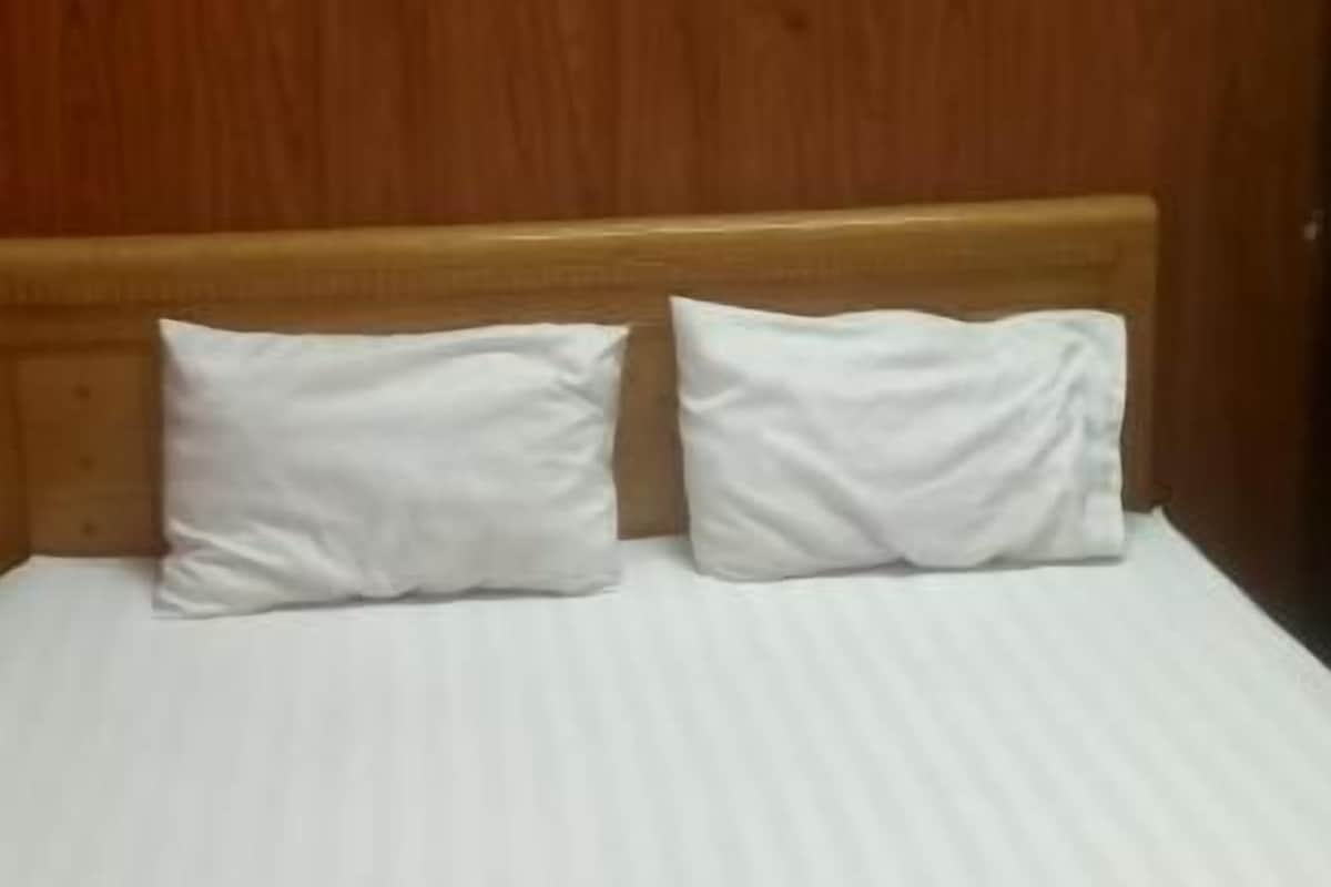 Ein Bett mit weißen Bettwäsche und einem hölzernen Kopfteil.