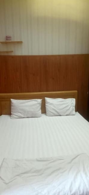 Ein Bett mit weißen Bettwäsche und einem hölzernen Kopfteil.