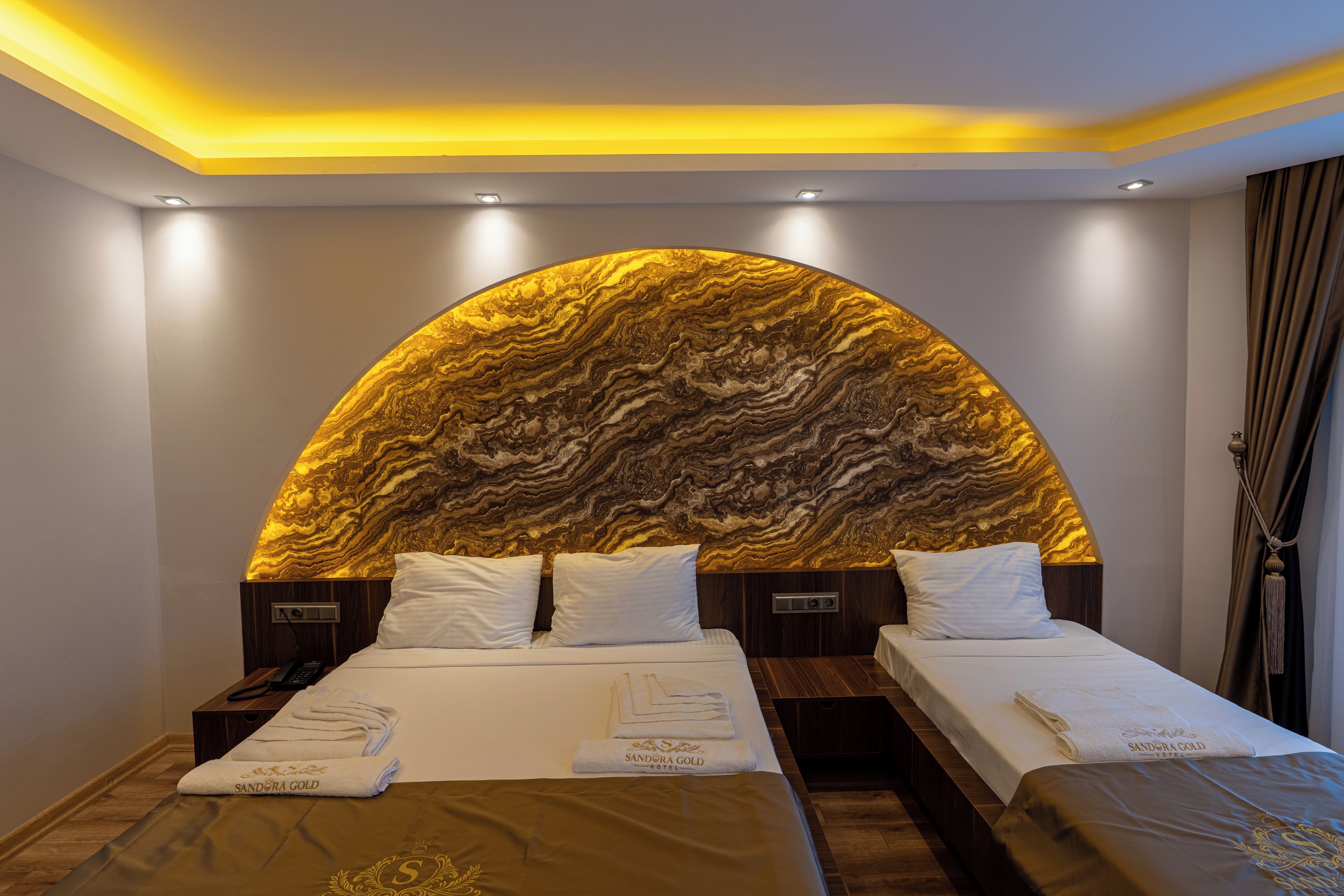 A hotel room with a large bed, two bedside tables, and a unique marble headboard.