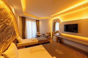 Habitación de hotel con cama, escritorio, televisor y zona de estar.