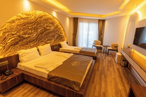 Una habitación de hotel con una cama grande, una cama más pequeña, un escritorio, una silla, un televisor y un mural grande en la pared.