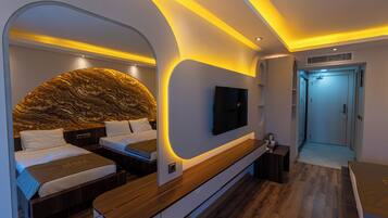 Un dormitorio moderno con cabecera curva, televisor de pantalla plana, banco de madera y vestidor.