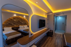 Un dormitorio moderno con cabecera curva, televisor de pantalla plana, banco de madera y vestidor.