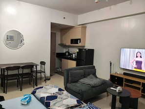 A modern living room with a sofa, a TV, a dining area, and a kitchen. - Your Cozy Nest in Novaliches-SMDC Hills Residences Novaliches (Quezon City)