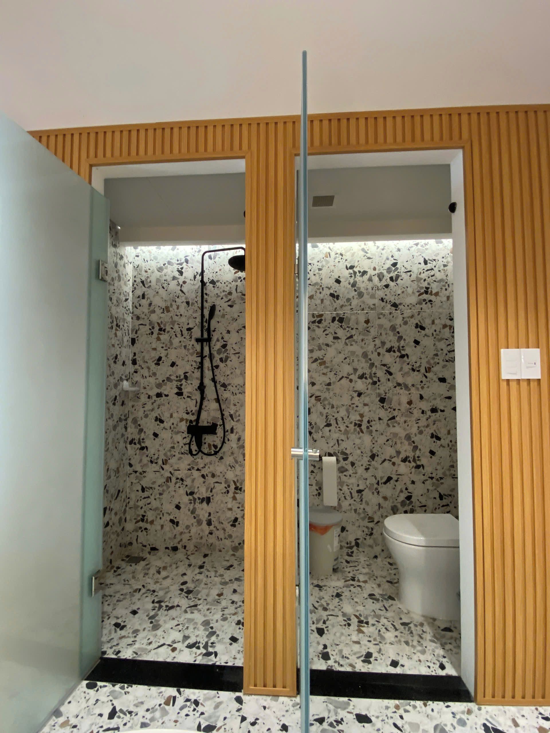 A bathroom with a shower, toilet, and a towel rack.