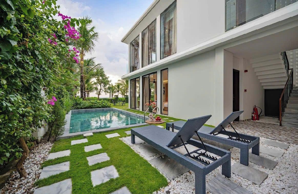 Una casa moderna con piscina, poltroncini da relax e una scala che conduce al piano superiore.