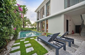 A modern house with a swimming pool, lounge chairs, and a staircase leading to the upper floor. - Song Thu Villa Hoi An (Hoi An)