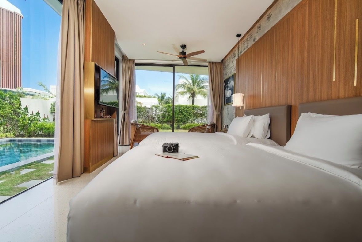 A large bed with a view of a swimming pool and palm trees.