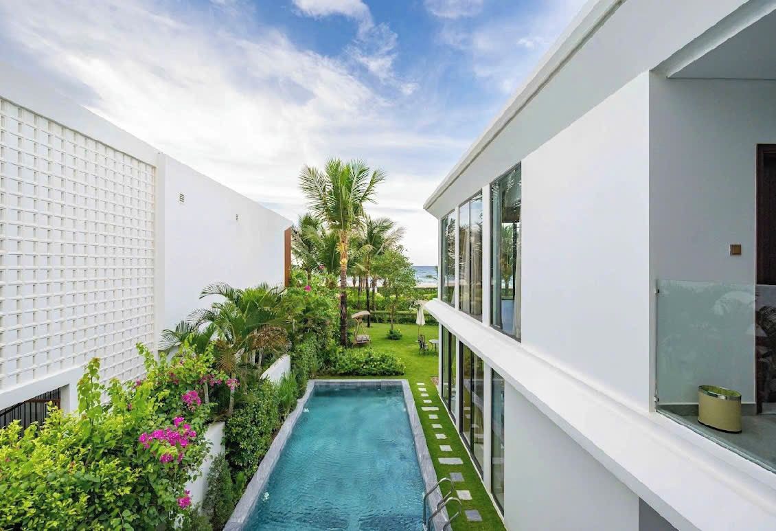 Un edificio moderno con piscina, rodeado de vegetación y palmeras.
