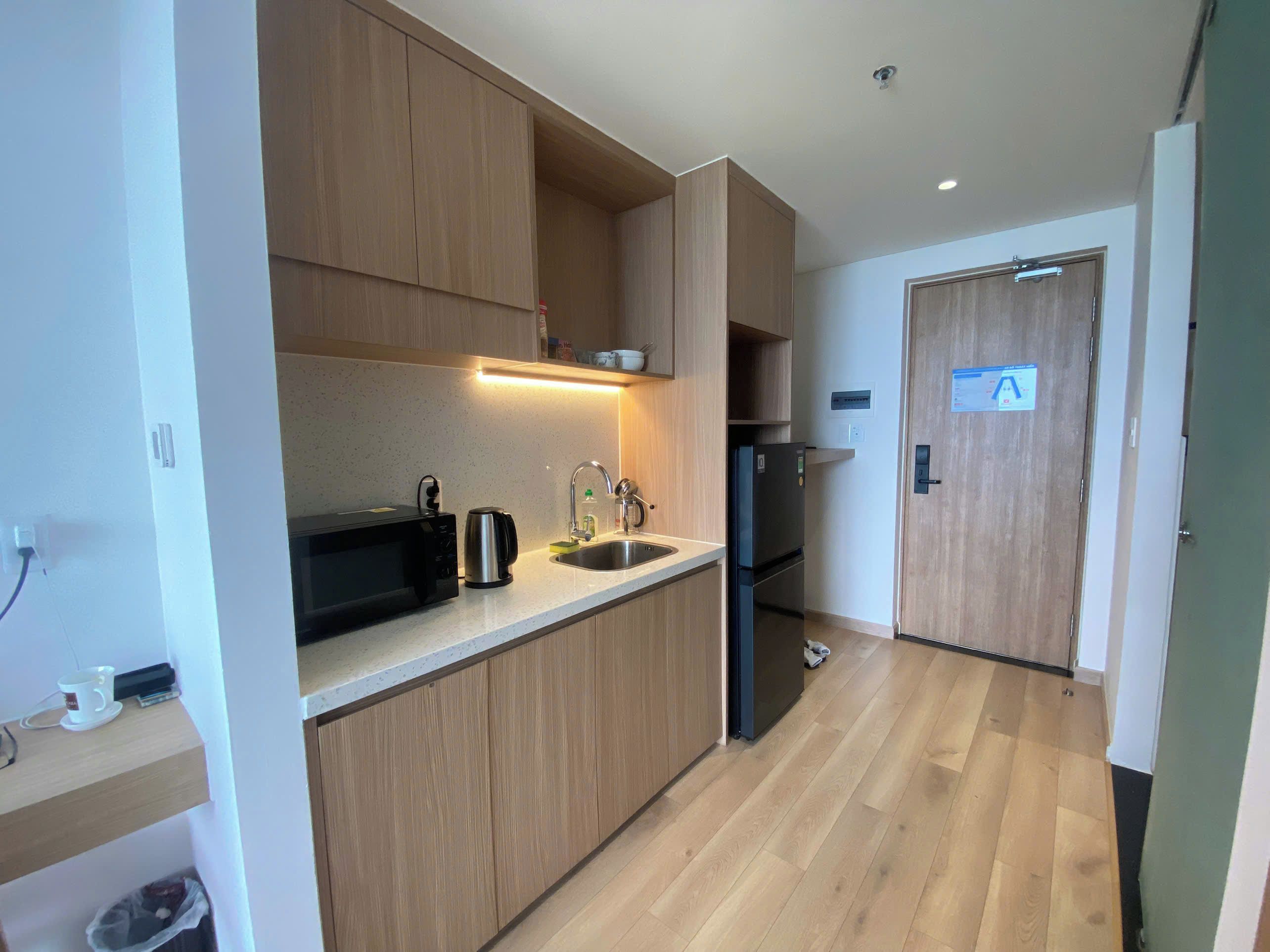 A modern kitchen with wooden cabinets, a stainless steel sink, and a black refrigerator.