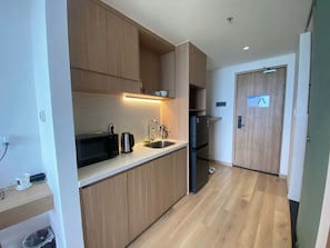 A modern kitchen with wooden cabinets, a stainless steel sink, and a black refrigerator. - Song Thu Villa Hoi An (Hoi An)