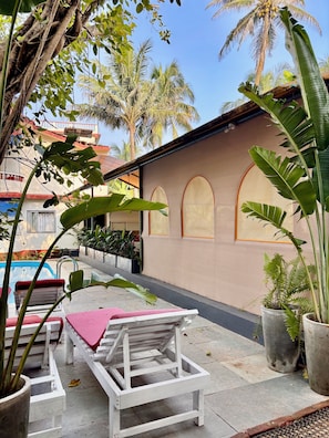 A poolside area with lounge chairs, a concrete floor, and potted plants. - Dmellos Seaview Home (Candolim)