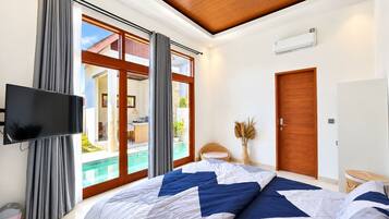 A bedroom with a large bed, a television, a sliding glass door to a balcony, and a wooden ceiling.