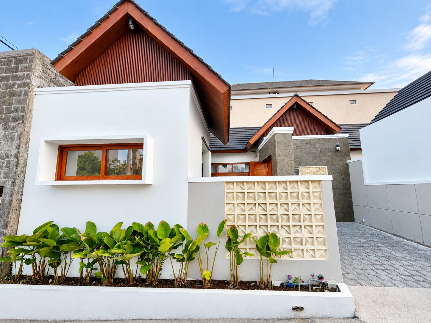 Un bâtiment moderne avec une façade blanche, un toit en bois et une petite fenêtre.